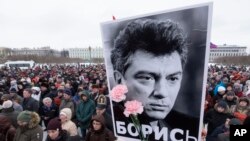 فروری دو ہزار سترہ کی اس فائل فوٹو میں لوگ روس کے اپوزیشن کے رہنما بورس نیمتسووکی تصویر اٹھائے ہوئے ہیں۔ 