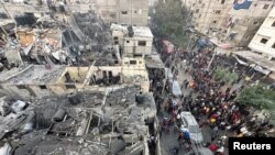 جنوبی غزہ کی پٹی میں رفح میں، اسرائیل اور حماس کے درمیان جاری تنازعے میں فلسطینی عمارتوں پر اسرائیلی فضائی حملے کے بعد لوگ تباہ شدہ عمارتوں کے ملبے کو چھان رہے ہیں فوٹو اے ایف پی ۔ 12 دسمبر 2023۔
