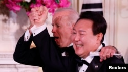 Tổng thống Hoa Kỳ Joe Biden (phía sau) và Tổng thống Hàn Quốc Yoon Suk Yeol bày tỏ cảm xúc hào hứng tại Quốc yến ở Nhà Trắng, trong chuyến thăm của ông Yoon Suk Yeol tới Hoa Kỳ vào ngày 26 tháng 4 năm 2023.