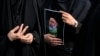 ایک ایرانی خاتون ہیلی کاپٹر حادثے میں ہلاک ہونے والے صدر ابراہیم ریئسی کا پوسٹر اٹھائے ہوئے ہے۔ 20 مئی 2024