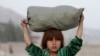 ایک افغان بچی سر پر سامان لاد کر پہنچا رہی ہے۔ فائل فوٹو