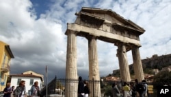 یونان کے شہر ایتھنز میں واقع رومی سلطنت کے دور کے ایک قدیم دروازے کو دیکھنے کے لیے سیاحوں کا ہجوم۔ فائل فوٹو