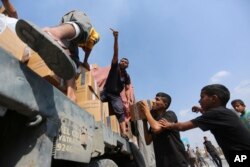 غزہ میں رفح کراسنگ کے قریب فلسطینی ایک ٹرک پر سے امدادی سامان اتار رہے ہیں۔ 2 نومبر 2023