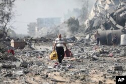 غزہ کے مضافات میں بمباری کے بعد ایک فلسطینی اپنا بچا کچا سامان نکال کر لا رہا ہے۔ 20 اکتوبر 2023