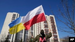Người biểu tình phất cờ Ba Lan và Ukraine trước nơi ở của các nhà ngoại Nga ở Warsaw, 13/3/2022.
