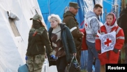 Một người phụ nữ di tản khỏi nhà máy thép Azovstal ở Mariupol với một thành viên của Ủy ban Chữ Thập Đỏ Quốc tế (ICRC) và một quân nhân của quân đội thân Nga đi cùng tại một trung tâm lưu trú tạm thời ở làng Bezimenne, ở Vùng Donetsk, Ukraine, ngày 6 tháng 5 năm 2022.