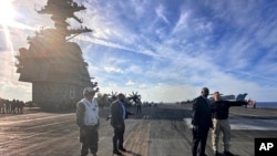 Bộ trưởng Quốc phòng Hoa Kỳ Lloyd Austin (thứ hai, bên phải) nói chuyện với chỉ huy của USS Gerald R. Ford, Đại úy Hải quân Rick Burgess (phải) trong chuyến thăm không báo trước tới con tàu vào ngày 20 tháng 12 năm 2023.