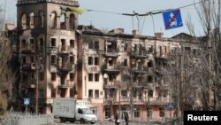 Người dân địa phương đi ngang qua một toà nhà bị tấn công ở thành phố cảng Mariupol, Ukraine, vào ngày 3/4/2022