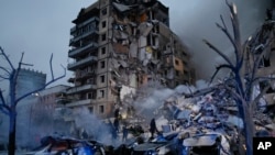 Các nhân viên ứng cứu khẩn cấp dọn đống đổ nát sau khi một phi đạn của Nga bắn trúng một tòa nhà chung cư khiến nhiều người chôn vùi dưới đống đổ nát ở Dnipro, Ukraine, ngày 14 tháng 1 năm 2023.