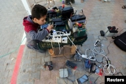 ایک فلسطینی بچہ ایک فری سروس اسپاٹ سے اپنا فون چارج کر رہا ہے ، فائل فوٹو