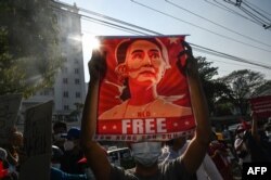 یانگون،میانمار میں احتجاج کے دوران ایک احتجاجی سوچی کی تصویر کا پوسٹر اٹھائے ہوئے فائل فوٹو