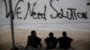 Các di dân ngồi bên dưới một biểu ngữ 'Chúng tôi cần giải pháp' phía trước sân vận động Thế vận hội ở Faliro, nam Athens,ngày 15/12/2015. 