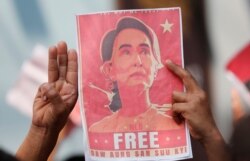 Dân Myanmar ở Thái Lan mang ảnh của lãnh đạo Aung San Suu Kyi đi biểu tình, họ giơ 3 ngòn tay chào, biểu tượng phản kháng quân đảo chính, trước sứ quán Myanmar ở Bangkok, Thái Lan, ngày 8/2/2021.