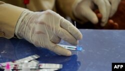 سندھ کے شہر رتو ڈیرو کے ایک ہسپتال میں ایچ آئی وی ٹیسٹ کے دوران ڈاکٹر خون کے نمونے کا معائنہ کر رہا ہے ۔ فائل فوٹو اے ایف پی