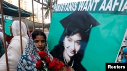 عافیہ صدیقی کی رہائی کا مطالبہ کرنے والی ایک خاتون ان کی تصویر کا پوسٹر اٹھائے ہوئے، فائل فوٹو
