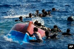 تارکین وطن بحیرہ روم عبور کرتے ہوئے ایک اطالوی جزیرے پر اپنی ڈوبی ہوئی کشتی کے گرد تیر رہے ہیں، فوٹو اے پی، 11 اگست 2022