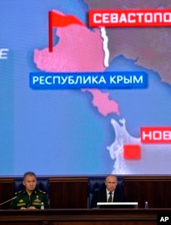 Tổng thống Nga Vladimir Putin (phải), và Bộ trưởng Quốc phòng Sergei Shoigu, chủ trì một cuộc họp với các giới chức quân sự hàng đầu ở Moscow, Nga, phía sau là bản đồ khu vực Cộng hòa Crimea, 19/12/2014.
