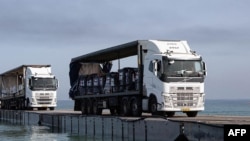 امریکہ کی جانب سے سمندر میں بنائے گئے عارضی گھاٹ سے امدادی سامان سے لدے ٹرک غزہ میں آ رہے ہیں۔ 