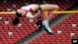 Một nhân viên bảo vệ nhìn nữ vận động viên nhảy cao Nga Elena Slesarenko tại sân vận động quốc gia của Trung Quốc, Bắc Kinh.