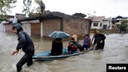 Trẻ em và phụ nữ được đưa qua một khu vực bị ngập lụt đến nơi an toàn hơn tại Srinagar, Ấn Độ, ngày 4/9/2014. 