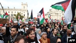 Người biểu tình giơ biểu ngữ và vẫy cờ Palestine tại Quảng trường Nghị viện sau khi tham gia 'Tuần hành vì Palestine' ở London vào ngày 28 tháng 10 năm 2023, để kêu gọi hưu chiến trong cuộc xung đột giữa Israel và Hamas.