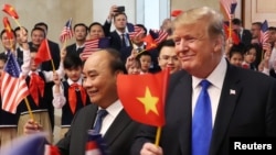 Tư liệu - Tổng thống Mỹ Donald Trump và Thủ tướng Việt Nam Nguyễn Xuân Phúc vẫy cờ khi được các em học sinh chào đón tại trụ sở Văn phòng Chính phủ ở Hà Nội, ngày 27 tháng 2, 2019.