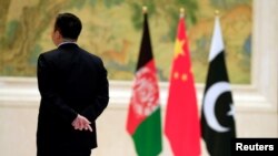 26 دسمبر 2017 کو بیجنگ میں چین-افغانستان اورپاکستان کےوزرائے خارجہ کے درمیان مذاکرات کے دوران ایک سیکیورٹی اہل کار افغان، چینی اور پاکستانی جھنڈوں کے قریب کھڑا ہے۔