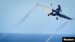 امریکی جیٹ ایف 18 طیارہ بردار بحری جہاز کے عشرے سے پرواز کر رہا ہے۔ فائل فوٹو