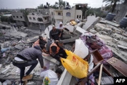 غزہ کی پٹی کے وسطی علاقے دیر البلح میں اسرائیلی بمباری کے بعد لوگ عمارتوں کے ملبے سے بچی کچی قابل استعمال چیزیں ڈھونڈ رہے ہیں۔ 13 مارچ 2024