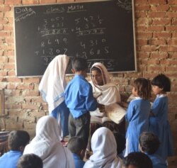 ایک دیہی اسکول میں ٹیچر بچوں کو پڑھا رہی ہے۔