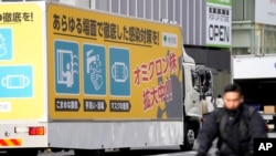 ٹوکیو کی ایک مصروف سڑک پر کھڑے ایک ٹرک میں اومیکرون سے بچاؤ کے بارے میں احتیاطی تدابیر درج ہیں۔ 28 جنوری 2022