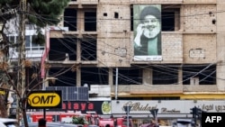 لبنانی عسکریت پسند تحریک حزب اللہ کے رہنما حسن نصراللہ کی ایک تصویر،ایک عمارت پر لٹکی ہوئی ہے جو اس ڈرون حملے کی جگہ کے قریب ہے جہاں حماس کے نائب رہنما صالح العروی کو نشانہ بنایا گیا تھا۔
