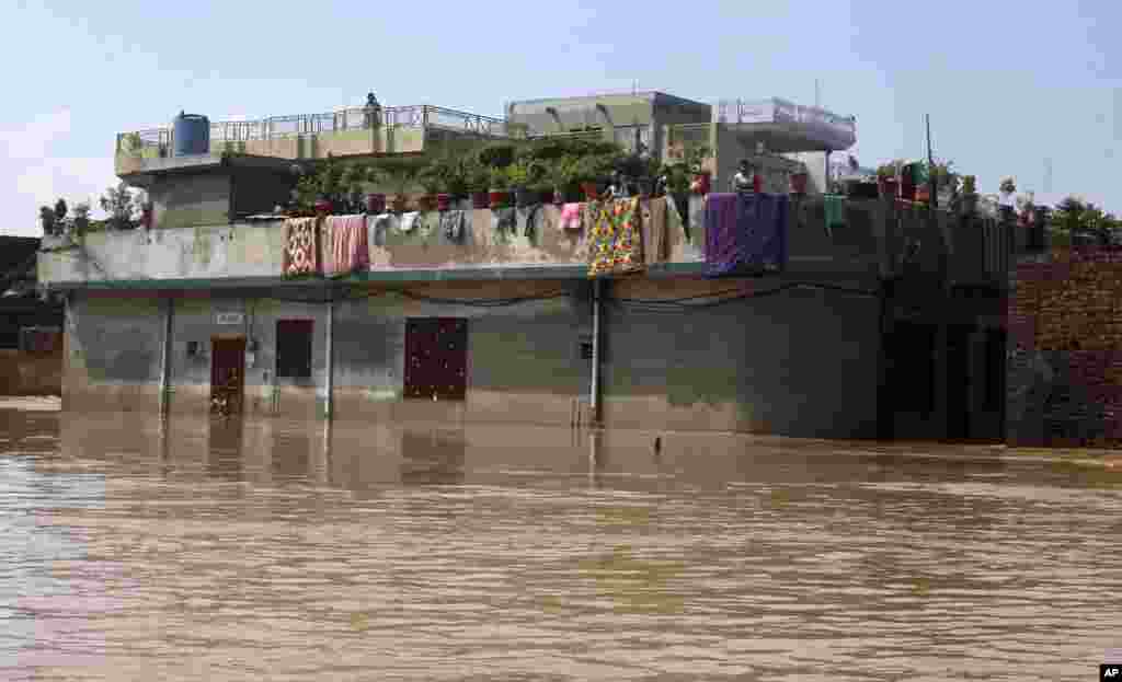 Cư dân chờ đợi để được sơ tán ở tầng trn chờ đợi ở tầng trên cùng của căn nhà bị ngập vì mưa mùa ở Wazirabad, khoảng 100 km (65 dặm) về phía bắc Lahore, Pakistan, ngày 7/9/2014.