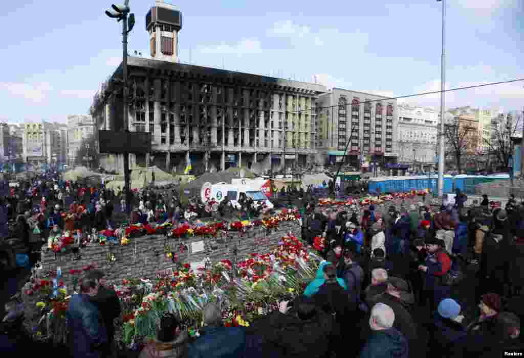 Người dân Ukraina đặt hoa tưởng niệm các nạn nhân tại một tường chắn dùng làm chướng ngại vật trong các cuộc biểu tình hồi gần đây ở trung tâm thủ đô Kiev, ngày 24/2/2014.