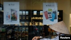 Một người bán hàng rong đi qua một cửa hàng Apple ở Hà Nội trong bức ảnh chụp ngày 24/4/2014. Việc tuyển dụng của Apple ở hai thành phố lớn đang làm dấy lên nghi vấn hãng công nghệ hàng đầu của Mỹ muốn mở nhà máy ở Việt Nam.