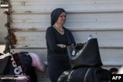 غیر ملکی پاسپورٹ رکھنے والی ایک فلسطینی خاتون رفح کراسنگ پر مصر جانے کی منتظر ہے ، فوٹو اے ایف پی