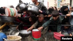 Trẻ em Palestine chờ nhận thức ăn do một nhà bếp từ thiện nấu trong bối cảnh thiếu nguồn cung cấp thực phẩm, khi cuộc xung đột đang diễn ra giữa Israel và nhóm Hồi giáo Palestine Hamas vẫn tiếp diễn, tại Rafah, ngày 13/2/2024.
