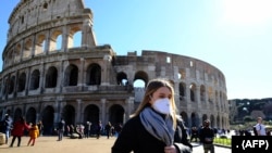 Du khách mang khẩu trang bên ngoài thắng cảnh Colosseo ở Rome ngày 28/2/2020 giữa dịch Covid-19. (Photo by Andreas SOLARO / AFP)