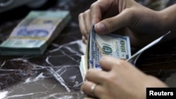 Nhân viên ngân hàng đếm đồng đôla Mỹ tại một ngân hành ở Hà Nội, ngày 12/08/2015. 