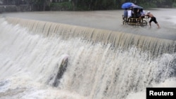 Cư dân vượt qua một con đập bị nước lũ dâng cao vì bão Koppu tại thành phố Las Pinas ở Manila, ngày 19/10/2015.