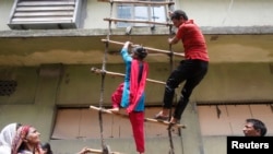 Công nhân của công ty may mặc Envoy Group thao diễn về cách chiếc leo thang tạm được dùng như một cách thoát khi có hỏa hoạn trong một cuộc biểu tình phản đối ở Dhaka 10/6/13