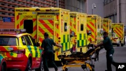 مشرقی لندن میں واقع رائل لندن ہاسپیٹل کے باہر کھڑی ایمبولنسز سے مریضوں کو اسپتال منتقل کیا جا رہا ہے۔ 6 جنوری 2022