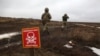 
یوکرین کے فوجی ایسی جگہ سے گزر رہے ہیں جہاں ایک انتباہی بورڈ لگا ہے کہ محتاط رہیے روس نے بارودی سرنگیں بچھا رکھی ہیں (فوٹو اے ایف پی)

