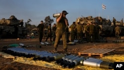 اسرائیلی فوجی اتوار، 31 دسمبر، 2023 کو غزہ کی سرحد کے قریب جنوبی اسرائیل میں ایک اسٹیجنگ ایریا میں ایک ٹینک پر گولے لوڈ کر رہے ہیں۔
