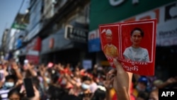 Dân chúng giương ảnh bà Aung San Suu Kyi (phải) và Tổng thống Myanmart Win Myint trong một cuộc biểu tình chống đảo chính quân sự ở Yangon ngày 6/2/2021. (Photo by YE AUNG THU / AFP)