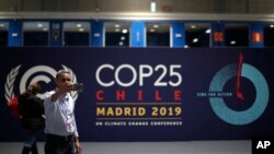 اسپین کے شہر میڈرڈ میں ہونے والی عالمی گلوبل وارمنگ کانفرنس کے لوگو کے سامنے ایک شخص اپنی سیلفی بنا رہا ہے۔ یکم دسمبر 2019