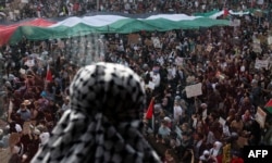 مظاہرے کے کئی شرکاٗ نے فلسطینی پرچم اٹھا رکھے تھے اور روایتی فلسطینی طرز کے سکارف پہن رکھے تھے